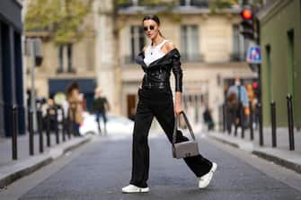 PARIS, FRANCE - OCTOBER 15: Olesya Senchenko wears sunglasses, a necklace, a white tank top, a black leather jacket, black pants / trousers, a gray Chanel quilted bag, white sneakers shoes, on October 15, 2021 in Paris, France.  (Photo by Edward Berthelot / Getty Images)