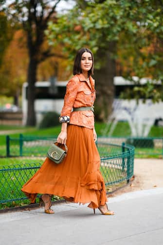 PARIS, FRANCE - SEPTEMBER 26: Camila Coelho wears an orange jacket with embroidered flowers patterns, a green khaki belt, a Chloe bag, pleated asymmetric long skirt, shoes, a necklace, outside Chloe, during Paris Fashion Week - Womenswear Spring Summer 2020 on September 26, 2019 in Paris, France. (Photo by Edward Berthelot/Getty Images)