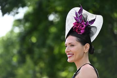 A race-goer wearing a hat poses upon her arrival to attend the thrid day, known as the Lady's day, of the Royal Ascot horse racing meet, in Ascot, west of London on June 16, 2022. (Photo by JUSTIN TALLIS / AFP) (Photo by JUSTIN TALLIS/AFP via Getty Images)