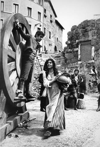 Adriano Celentano acting at the 'Marcello theater' for the musical comedy 'Rugantino', he is tied to a big wheel and Claudia Mori is near him holding a jug of water, Rome 1979. (Photo by Archivio Cicconi/Getty Images)