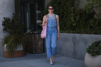 WEST HOLLYWOOD, CALIFORNIA - APRIL 21: Veronika Heilbrunner seen wearing a black sunglasses, pearl earrings, a grey top from Zara, a blue denim overall from Calvin Klein, a light pink Chanel 22 shopper bag and blue denim ballerinas from Chanel on April 21, 2022 in West Hollywood, California. (Photo by Jeremy Moeller/Getty Images)