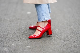 PARIS, FRANCE - APRIL 04: Maria Rosaria Rizzo @lacoquetteitalienne wears a beige buttoned long belted trench coat, blue faded denim large pants, red shiny varnished leather strappy block heels ballerinas / shoes, during a street style fashion photo session, on April 04, 2022 in Paris, France. (Photo by Edward Berthelot/Getty Images)