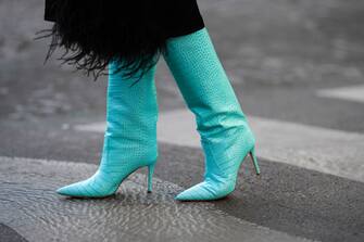 PARIS, FRANCE - FEBRUARY 09: Katie Giorgadze wears a black satin midi skirt with embroidered feathers from Trim Choux, turquoise blue shiny leather crocodile print pattern pointed heels high boots from Bettina Vermillon, during a street style fashion photo session, on February 09, 2022 in Paris, France. (Photo by Edward Berthelot/Getty Images)