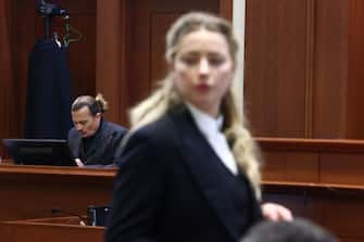 TOPSHOT - US actress Amber Heard (R) speaks to her legal team as US actor Johhny Depp (L) returns to the stand after a lunch recess during the 50 million US dollar Depp vs Heard defamation trial at the Fairfax County Circuit Court in Fairfax, Virginia, April 21, 2022. - Actor Johnny Depp is suing ex-wife Amber Heard for libel after she wrote an op-ed piece in The Washington Post in 2018 referring to herself as a public figure representing domestic abuse. (Photo by Jim LO SCALZO / POOL / AFP) (Photo by JIM LO SCALZO/POOL/AFP via Getty Images)