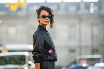 PARIS, FRANCE - OCTOBER 04: Anna Rosa Vitiello wears black sunglasses from Chanel, black shiny leather heart logo earrings from Chanel, a black shiny leather quilted jacket from Chanel, a neon pink shiny varnished leather micro crossbody bag from Chanel, black shiny leather large pants, outside Chanel, during Paris Fashion Week - Womenswear Spring/Summer 2023, on October 04, 2022 in Paris, France. (Photo by Edward Berthelot/Getty Images)