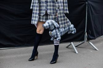 PARIS, FRANCE - OCTOBER 03: Kozue Akimoto wears checkered blazer, jacket, shorts, tie, white button shirt, dog shaped bag, knee high socks, heels outside Thom Browne during Paris Fashion Week - Womenswear Spring/Summer 2023 : Day Eight on October 03, 2022 in Paris, France. (Photo by Christian Vierig/Getty Images)