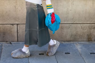 PARIS, FRANCE - SEPTEMBER 30: A guest wears blue elephant bag, white v neck knit, grey skirt, faux fur shoes outside Loewe during Paris Fashion Week - Womenswear Spring/Summer 2023 : Day Five on September 30, 2022 in Paris, France. (Photo by Christian Vierig/Getty Images)