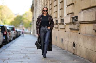 PARIS, FRANCE - OCTOBER 26: Diane Batoukina wears black sunglasses, a black t-shirt, a dark brown shiny leather long coat, a black shiny grained leather Kelly small belt from Hermes, black denim large pants, a black shiny leather Timeless handbag from Chanel, black shiny leather heels ankle boots , during a street style fashion photo session, on October 26, 2022 in Paris, France. (Photo by Edward Berthelot/Getty Images)
