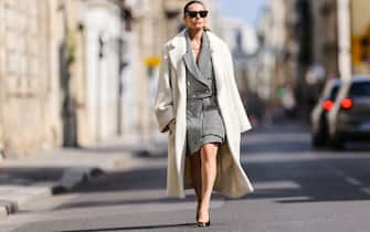 PARIS, FRANCE - AUGUST 15: Julia Comil wears a white long wool "bouclÃ©" oversized coat by Dorothee Schumacher, a black and white houndstooth graphic print cropped blazer jacket by Dorothee Schumacher, a black and white houndstooth graphic print knee high skirt, a Cleo white patent leather shoulder bag with triangle Prada logo by Prada, blade slingback pointed pumps in black patent leather with metallic silver tips by Saint Laurent, on August 15, 2021 in Paris, France. (Photo by Edward Berthelot/Getty Images)