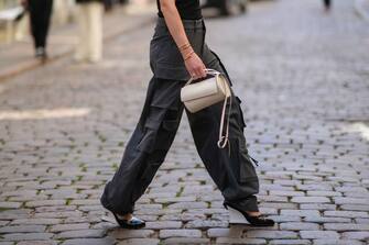 1414583326 COPENHAGEN, DENMARK - AUGUST 11: Annabel Rosendahl wears a black turtleneck / shoulder-off / sleeveless / body top, dark gray large cargo pants, a gold watch, gold rings, gold Love bracelet from Cartier, a gold Juste Un Clou bracelet from Cartier, a white matte leather tube handbag, black shiny varnished leather pointed with white wedge heels shoes from Chanel , outside Mark Kenly Domino Tan during Copenhagen Fashion Week Spring/Summer 2023, on August 11, 2022 in Copenhagen, Denmark. (Photo by Edward Berthelot/Getty Images)