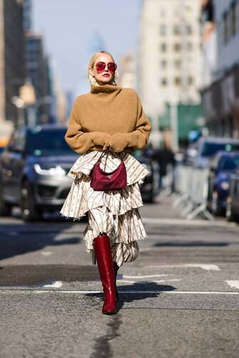1205190494 NEW YORK, NEW YORK - FEBRUARY 09: Leonie Hanne wears a brown turtleneck wool oversized pullover, a purple Prada bag, a ruffled skirt, burgundy leather high pointy boots, outside Brock Collection, during New York Fashion Week Fall Winter 2020, on February 09, 2020 in New York City. (Photo by Edward Berthelot/Getty Images)