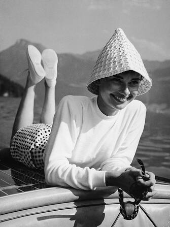 Portrait of Belgian-born American actress Audrey Hepburn (1929 - 1993) wears a peculiar hat and lies on the back of a motorboat on a lake in Switzerland, early 1950s. (Photo by Pictorial Parade/Getty Images)