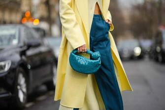 PARIS, FRANCE - MARCH 02: Leonie Hanne wears a pale yellow ribbed turtleneck / asymmetric cropped pullover, a pale yellow long coat, high waist blue large suit pants, a blue shiny braided leather Jodie handbag from Bottega Veneta, outside Rochas, during Paris Fashion Week - Womenswear F/W 2022-2023, on March 02, 2022 in Paris, France. (Photo by Edward Berthelot/Getty Images)