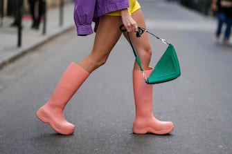 PARIS, FRANCE - APRIL 14: Almuneda Lapique wears a purple denim oversized jacket from Temps Des Cerises, pale yellow tweed high waist shorts, a silver ring, a green shiny leather Triangle handbag from Prada, pale pink Puddle Rubber rain boots from Bottega Veneta , during a street style fashion photo session, on April 14, 2022 in Paris, France. (Photo by Edward Berthelot/Getty Images)