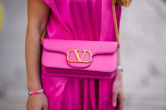PARIS, FRANCE - APRIL 20: Maria Rosaria Rizzo wears a pink shiny leather crossbody bag from Valentino, a silver watch from Role, silver rings, a pink and blue bracelet in shape of heart, a pink fuchsia shiny silk oversized kimono from Balenciaga, during a street style fashion photo session, on April 20, 2022 in Paris, France. (Photo by Edward Berthelot/Getty Images)