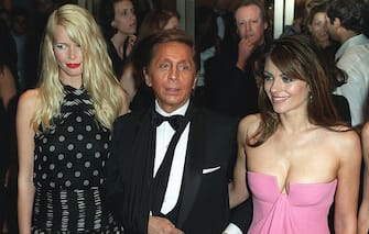 NEW YORK, UNITED STATES:  Valentino(C) is surrounded by models Claudia Schiffer (L) and Elizabeth Hurley (R) as he arrives at the American Fashion Awards in New York 15 June 2000. Valentino is to receive the "Lifetime Achievement Award" from the Council of Fashion Designers of America. AFP PHOTO/Doug KANTER (Photo credit should read DOUG KANTER/AFP via Getty Images)