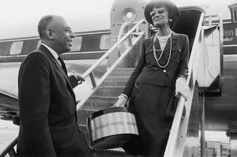 1957:  French fashion designer Coco Chanel says goodbye to American department store executive Stanley Marcus as she boards an airplane in Dallas, Texas. Chanel had been visiting for the opening of a new Neiman-Marcus store. She holds a package from the store.  (Photo by Shel Hershorn/Hulton Archive/Getty Images)