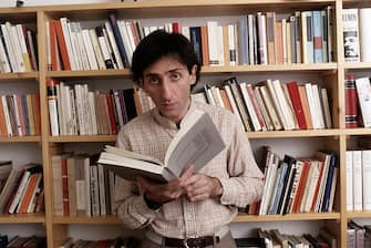 Italian singer-songwriter and director Franco Battiato holding a book in his hands in front of a bookcase. 1981. (Photo by Angelo Deligio/Mondadori via Getty Images)