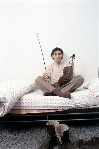 Italian singer-songwriter and director Franco Battiato sitting on the bed with a violin in his hand. 1981. (Photo by Angelo Deligio/Mondadori via Getty Images)
