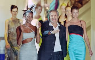 Italian fashio, designer Gianni Versace, with models, British Naomi Campbell and Canadian Linda Evangelista, acknowledges the audience at the end of the presentation of the Fall/Winter Haute Couture collections in Paris on July 6, 1996. (Photo by Thomas COEX / AFP)        (Photo credit should read THOMAS COEX/AFP via Getty Images)