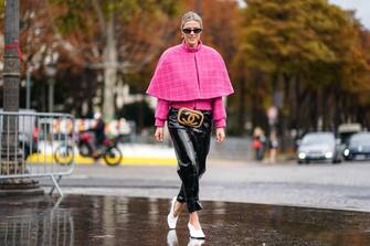PARIS, FRANCE - OCTOBER 01: Sofie Valkiers wears sunglasses, earrings, a pink tweed jacket, a pink short cape, a Chanel belt-bag, shiny black patent leather pants, white pointy heels, outside Chanel, during Paris Fashion Week - Womenswear Spring Summer 2020, on October 01, 2019 in Paris, France. (Photo by Edward Berthelot/Getty Images)
