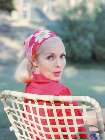 American actress Janet Leigh (1927 - 2004) looks over her shoulder as she sits in a lawn chair and wears a red floral print headscarf, late 1960s. (Photo by Hulton Archive/Getty Images)