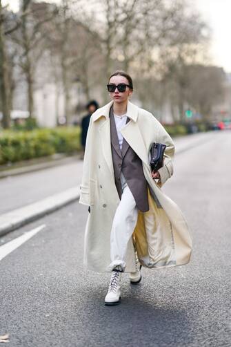 PARIS, FRANCE - JANUARY 19: Beatrice Gutu wears sunglasses, a white long coat, a brown jacket, white shoes, a bag, cuffed pants, outside Paul Smith, during Paris Fashion Week - Menswear Fall/Winter 2020-2021, on January 19, 2020 in Paris, France. (Photo by Edward Berthelot/Getty Images)