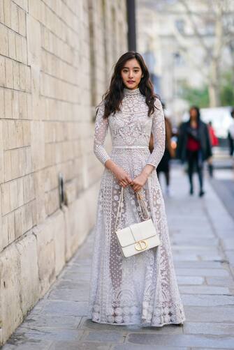PARIS, FRANCE - JANUARY 20: Yuko Araki  wears a white lace mesh dress with floral embroidery, a "CD" Dior bag, outside Dior, during Paris Fashion Week - Haute Couture Spring/Summer 2020, on January 20, 2020 in Paris, France. (Photo by Edward Berthelot/Getty Images )
