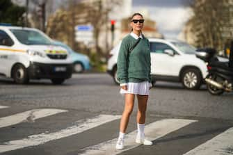 PARIS, FRANCE - MARCH 03: Sophia Roe wears sunglasses, a white polo shirt, a green pullover from Lacoste, a white pleated mini skirt, white socks, sneakers, outside Lacoste, during Paris Fashion Week - Womenswear Fall/Winter 2020/2021 on March 03, 2020 in Paris, France. (Photo by Edward Berthelot/Getty Images)