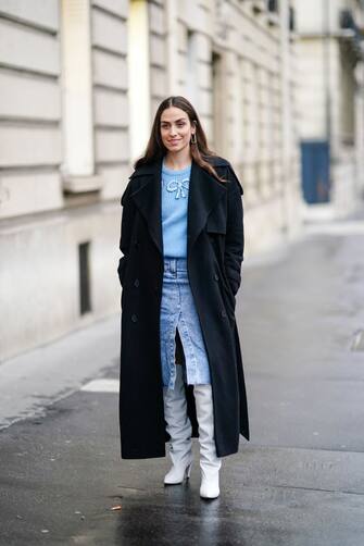 PARIS, FRANCE - FEBRUARY 28: Erika Boldrin wears a dark long coat, a blue pullover, a blue denim skirt, white leather long boots, outside Alessandra Rich, during Paris Fashion Week - Womenswear Fall/Winter 2020/2021, on February 28, 2020 in Paris, France. (Photo by Edward Berthelot/Getty Images)