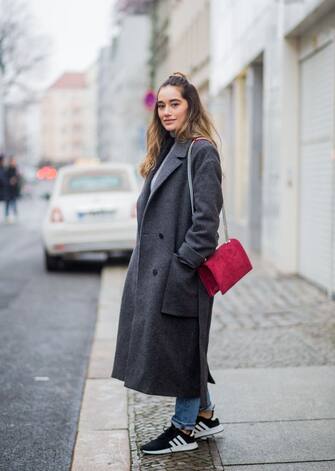 BERLIN, GERMANY - DECEMBER 16: Anna Sharypova wearing red Agneel bag, dark grey COS wool coat, Adidas sneaker, boyfriend denim jeans &other stories, top Uniqlo, on December 16, 2017 in Berlin, Germany. (Photo by Christian Vierig/Getty Images)