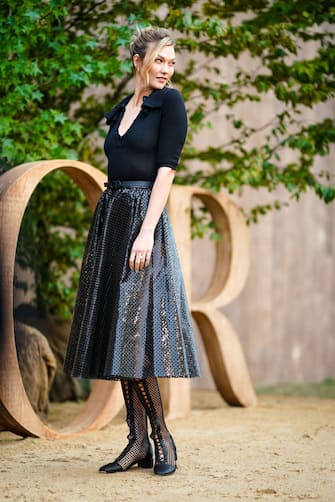 PARIS, FRANCE - SEPTEMBER 24: Karlie Kloss wears a black low neck top, a black shiny pleated glitter skirt, mesh boots, earrings, outside Dior, during Paris Fashion Week - Womenswear Spring Summer 2020, on September 24, 2019 in Paris, France. (Photo by Edward Berthelot/Getty Images)