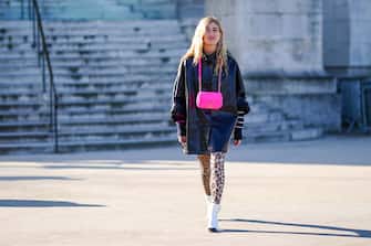 PARIS, FRANCE - JANUARY 21: Emili Sindlev wears earrings, a shiny black oversize coat, a neon-green Chanel bag, beige and brown leopard print leggings, white and black Chanel ankle-boots , outside Chanel, during Paris Fashion Week - Haute Couture Spring/Summer 2020, on January 21, 2020 in Paris, France. (Photo by Edward Berthelot/Getty Images )