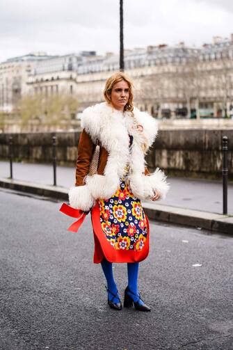 PARIS, FRANCE - FEBRUARY 27: Blanca Miro wears a brown coat with white fluffy parts, a red an yellow floral print skirt, a metallic bag, blue tights, black leather pointy shoes, outside Paco Rabanne, during Paris Fashion Week - Womenswear Fall/Winter 2020/2021, on February 27, 2020 in Paris, France. (Photo by Edward Berthelot/Getty Images)