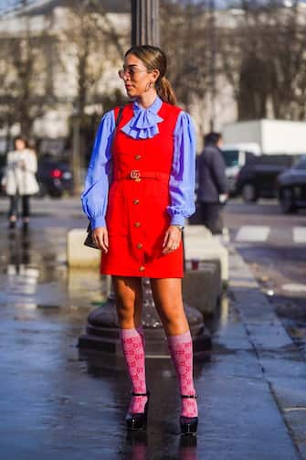 PARIS, FRANCE - MARCH 03: A guest wears earrings, a mauve ruffled shirt, a red sleeveless dress, a Gucci belt, Gucci monogram long socks, black shoes, outside Chanel, during Paris Fashion Week - Womenswear Fall/Winter 2020/2021 on March 03, 2020 in Paris, France. (Photo by Edward Berthelot/Getty Images)