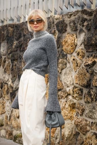 PARIS, FRANCE - FEBRUARY 28: Xenia Adonts wearing grey knit scarf, jumper, white boots and beige joggers outside the Loewe show during the Paris Fashion Week Womenswear Fall/Winter  on February 28, 2020 in Paris, France. (Photo by Hanna Lassen/Getty Images)