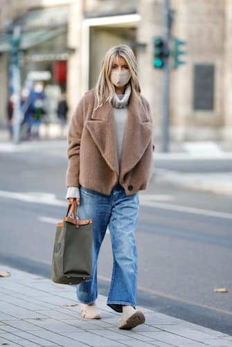 DUESSELDORF, GERMANY - NOVEMBER 13: Influencer Gitta Banko wearing a short camel colored teddy jacket by Liviana Conti, light blue denim jeans by Saint Laurent, knitted beige 2.0 speed sneaker by  Balenciaga, a beige cashmere turtleneck pullover by LaMaii Cashmere, a beige face mask and an olive green canvas peekaboo shopper by Fendi during a street style shooting on November 13, 2020 in Duesseldorf, Germany. (Photo by Streetstyleshooters/Getty Images)