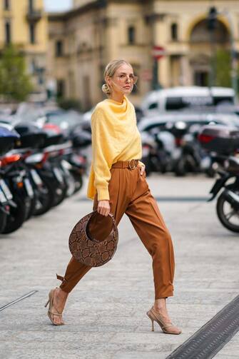 1187025259 MILAN, ITALY - SEPTEMBER 20: Leonie Hanne wears earrings, a fluffy yellow sweater with a scarf, rust-color pants, beige fishnet heeled pumps, a brown python pattern round handbag, outside the Sportmax show during Milan Fashion Week Spring/Summer 2020 on September 20, 2019 in Milan, Italy. (Photo by Edward Berthelot/Getty Images)