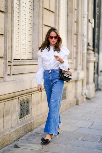 PARIS, FRANCE - SEPTEMBER 15: Therese Hellström wears red Celine sunglasses, a white shirt / blouse from H&M with large ruffled collar, a black leather Karl Lagerfeld bag with a chain and brown leopard print, blue denim flared jeans from Zara, pointy shoes with bow tie from Custommade, on September 15, 2020 in Paris, France. (Photo by Edward Berthelot/Getty Images)