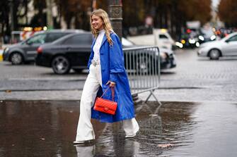 PARIS, FRANCE - OCTOBER 01: Emili Sindlev wears a blue long coat, a white top, a belt, a red quilted Chanel bag, white flared pants, outside Chanel, during Paris Fashion Week - Womenswear Spring Summer 2020, on October 01, 2019 in Paris, France. (Photo by Edward Berthelot/Getty Images)
