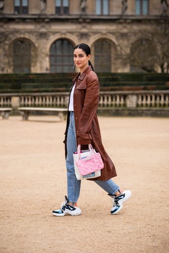 PARIS, FRANCE - JANUARY 20: Fiona Zanetti, wearing a white t-shirt, blue jeans, Louis Vuitton sneakers, pink Kenzo bag and brown long coat, is seen in the streets of Paris after the Kenzo show on January 20, 2019 in Paris, France. (Photo by Claudio Lavenia/Getty Images)