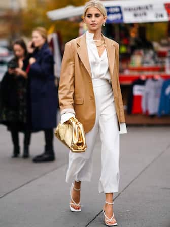 PARIS, FRANCE - SEPTEMBER 25: Caroline Daur wears earrings, necklaces, a camel leather oversized jacket, a white shirt, white wide-legs crop pants, white sandals, a shiny gold puff bag, outside Rochas, during Paris Fashion Week - Womenswear Spring Summer 2020 on September 25, 2019 in Paris, France. (Photo by Edward Berthelot/Getty Images)