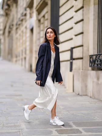 PARIS, FRANCE - JUNE 29: Geraldine Boublil wears a white pearl necklace from Coconut Love, a dark navy blue striped oversized blazer jacket from Gauge 81, a white lustrous silky shiny low-neck dress from Basilika, Hogan white and silver sneakers, on June 29, 2020 in Paris, France. (Photo by Edward Berthelot/Getty Images)