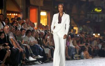 Maurizio degli Innocenti/Ansa 20060621 FLORENCE.- International model Naomi Campbell (C) and two unidentified male models display creations by fashion designer Roberto Cavalli during a fashion show at the 'Ponte Vecchio' (The Old Brigde). ansa maurizio degl'innocenti
20060621 - FIRENZE - SPE - MODA: CAVALLI, UN UOMO IN SCURO CHE SI SFOGA CON ACCESSORI. SFILATA SU PONTE VECCHIO. LO STILISTA, NON VENDO IL MARCHIO. Naomi Campbell apre la sfilata uomo di Roberto Cavalli, questa sera su Ponte Vecchio, a Firenze. ''Il Ponte Vecchio e' un luogo magico, un simbolo, e' qualcosa che ha resistito alla storia, quando l' Associazione Orafi mi ha offerto questo posto - racconta Cavalli - non nascondo che ho fatto anche una lacrimuccia. Sono un po' intimorito, ho quasi l'impressione che i nostri avi possano affacciarsi dalle finestre del sovrastante Corridoio Vasariano per giudicarmi. Per rispetto del luogo ho scelto una musica molto contenuta per accompagnare i modelli e, a fine sfilata, percorrero' il selciato in punta di piedi''.