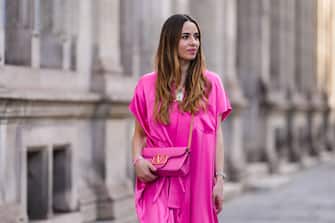 PARIS, FRANCE - APRIL 20: Maria Rosaria Rizzo wears a gold chain with large white pendant necklace, a pink shiny leather crossbody bag from Valentino, a silver watch, silver rings, a pink and blue bracelet in shape of heart, a pink fuchsia shiny silk oversized kimono from Balenciaga, during a street style fashion photo session, on April 20, 2022 in Paris, France. (Photo by Edward Berthelot/Getty Images)