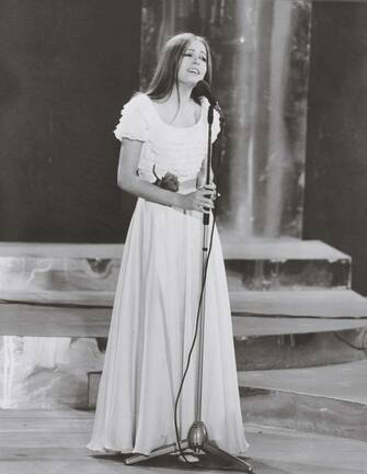 Italian singer Nada, born Nada Malanima, in a white dress with a red rose at her belt, sings Il cuore Ã¨ uno zingaro on the stage of the Sanremo music festival; with this song the emerging singer shall triumph in the music contest. Sanremo (IM), Italy, February 1971. (Photo by Mondadori via Getty Images)