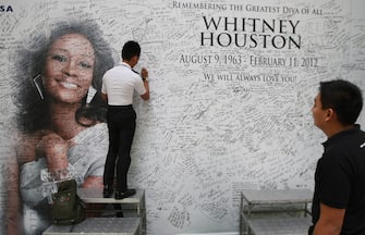 epa03108177 A Filipino fan signs a message wall with the image of late US singer Whitney Houston at a shopping mall in Quezon City, east of Manila, Philippines 16 February 2012. Houston, a Grammy Award winning singer, was found dead in her hotel room in Beverly Hills, California, USA on 11 February. She died at the age of 48.  EPA/ROLEX DELA PENA