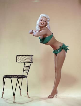 American film actor and sex symbol Jayne Mansfield (1933 - 1967) leans forward from the waist and clasps her hands together in a studio portrait, mid 1950's. She wears a green bikini and clear high-heel shoes. (Photo by Hulton Archive/Getty Images)