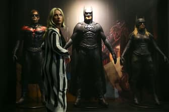 An employee poses in front of (L-R) a Robin costume worn by actor Chris O'Donnell in 'Batman and Robin' 1997 and designed by Bob Ringwood and Robert Turturice, a Batman costume worn by US actor George Clooney in 'Batman and Robin' 1997 and designed by Bob Ringwood and Robert Turturice and a Batgirl costume worn by US actress Alicia Silverstone in 'Batman and Robin' 1997 and designed by Bob Ringwood and Robert Turturice are displayed during a press preview of 'DC Comics Exhibition: Dawn of Super Heroes' at the O2 Arena in Greenwich, east London on February 22, 2018. / AFP PHOTO / Daniel LEAL-OLIVAS / RESTRICTED TO EDITORIAL USE - MANDATORY MENTION OF THE ARTIST UPON PUBLICATION - TO ILLUSTRATE THE EVENT AS SPECIFIED IN THE CAPTION        (Photo credit should read DANIEL LEAL-OLIVAS/AFP via Getty Images)