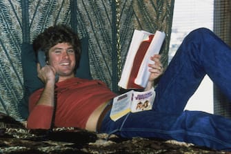 Actor and singer David Hasselhoff, at home in Hollywood, reading a script and an American football novel 'Semi Tough' while making a phone call, 1979. (Photo by Bob V. Noble/Fotos International/Archive Photo/Getty Images)